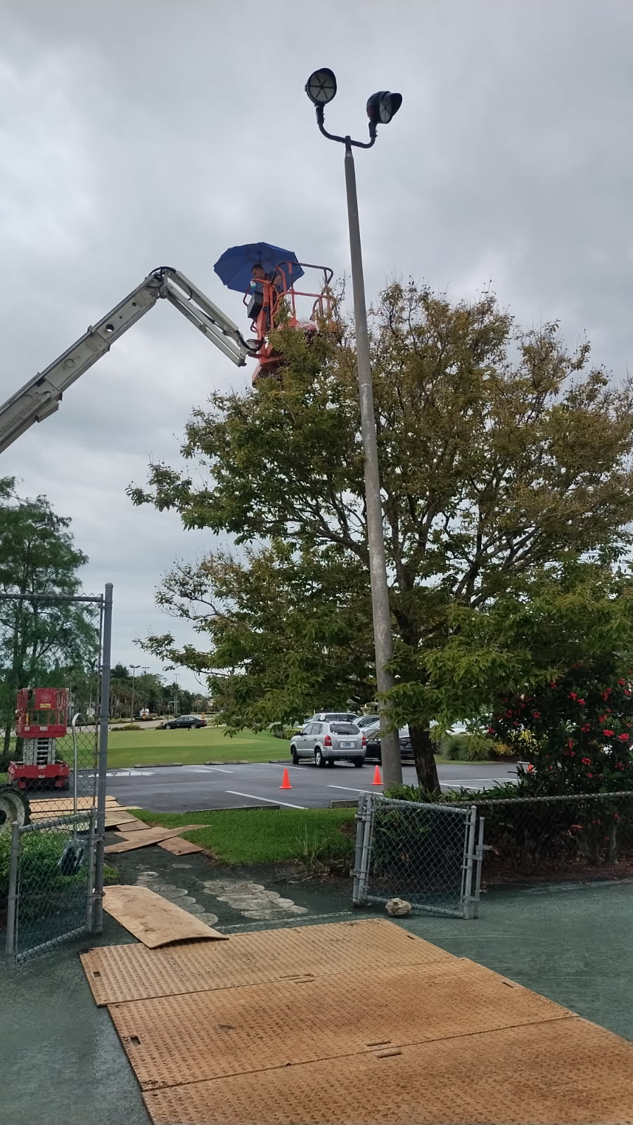 Dan House Electric servicing a parking-lot light pole from a lift