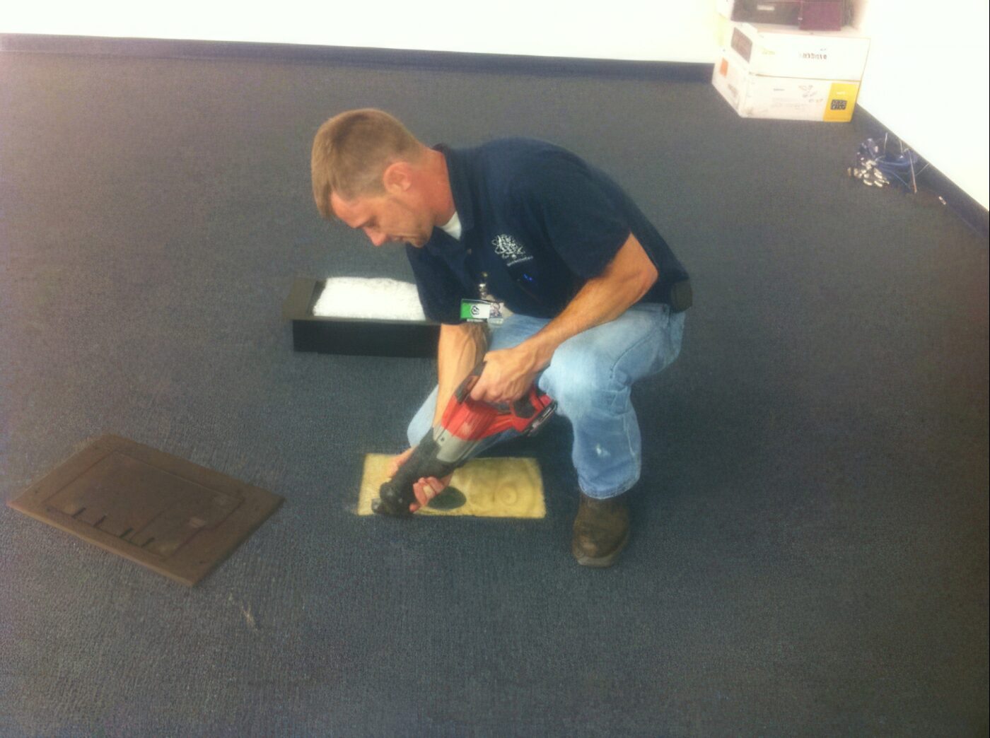 Dan House Electric technician inspecting and updating an existing floor outlet